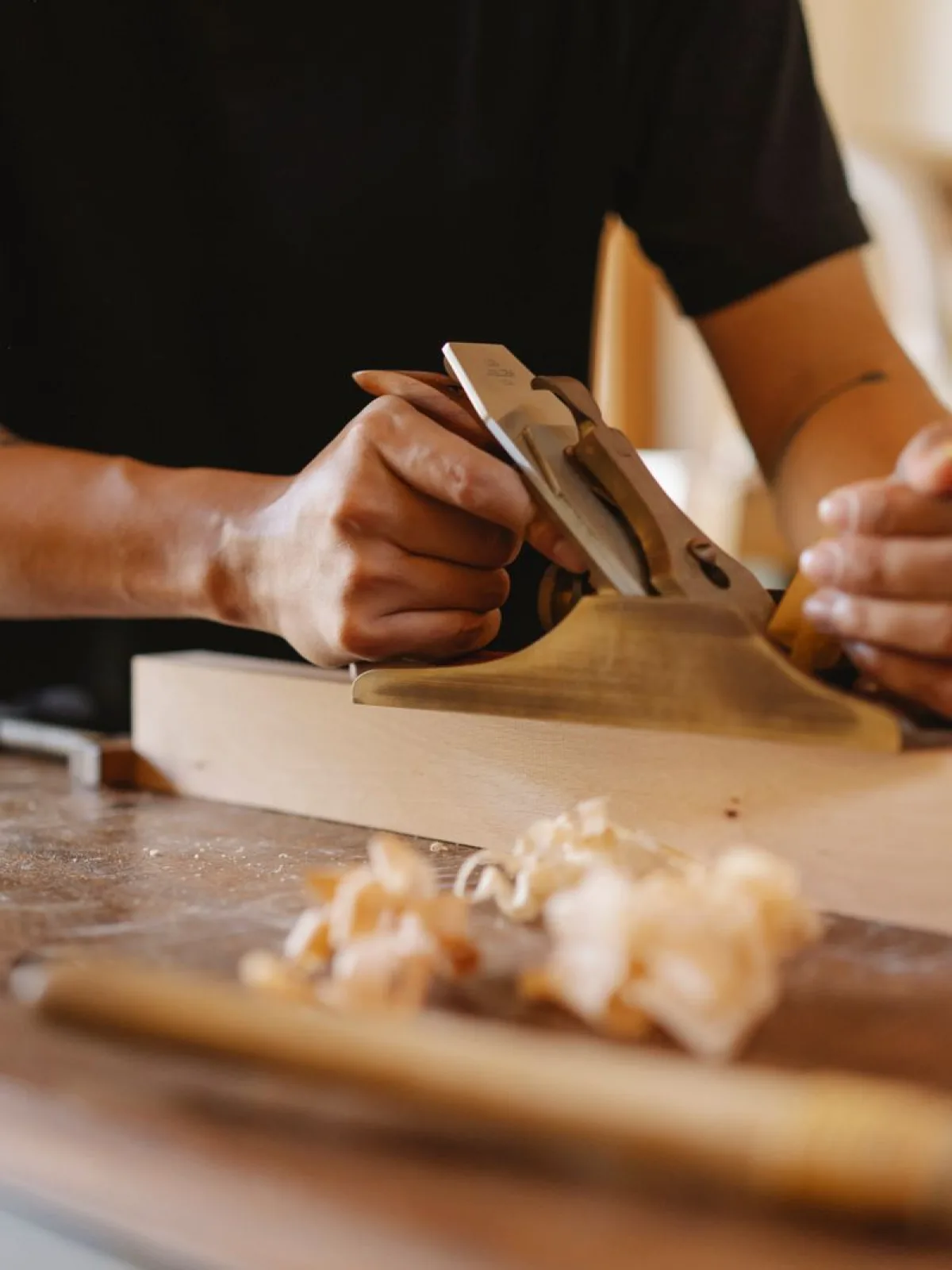 A maker planing a solid oak board by hand in the workshop